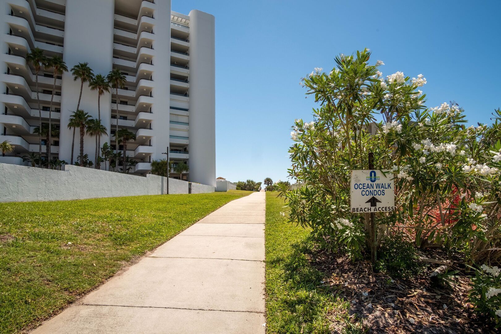 A pathway leading to a building with a sign indicating an ocean walk and beach access.