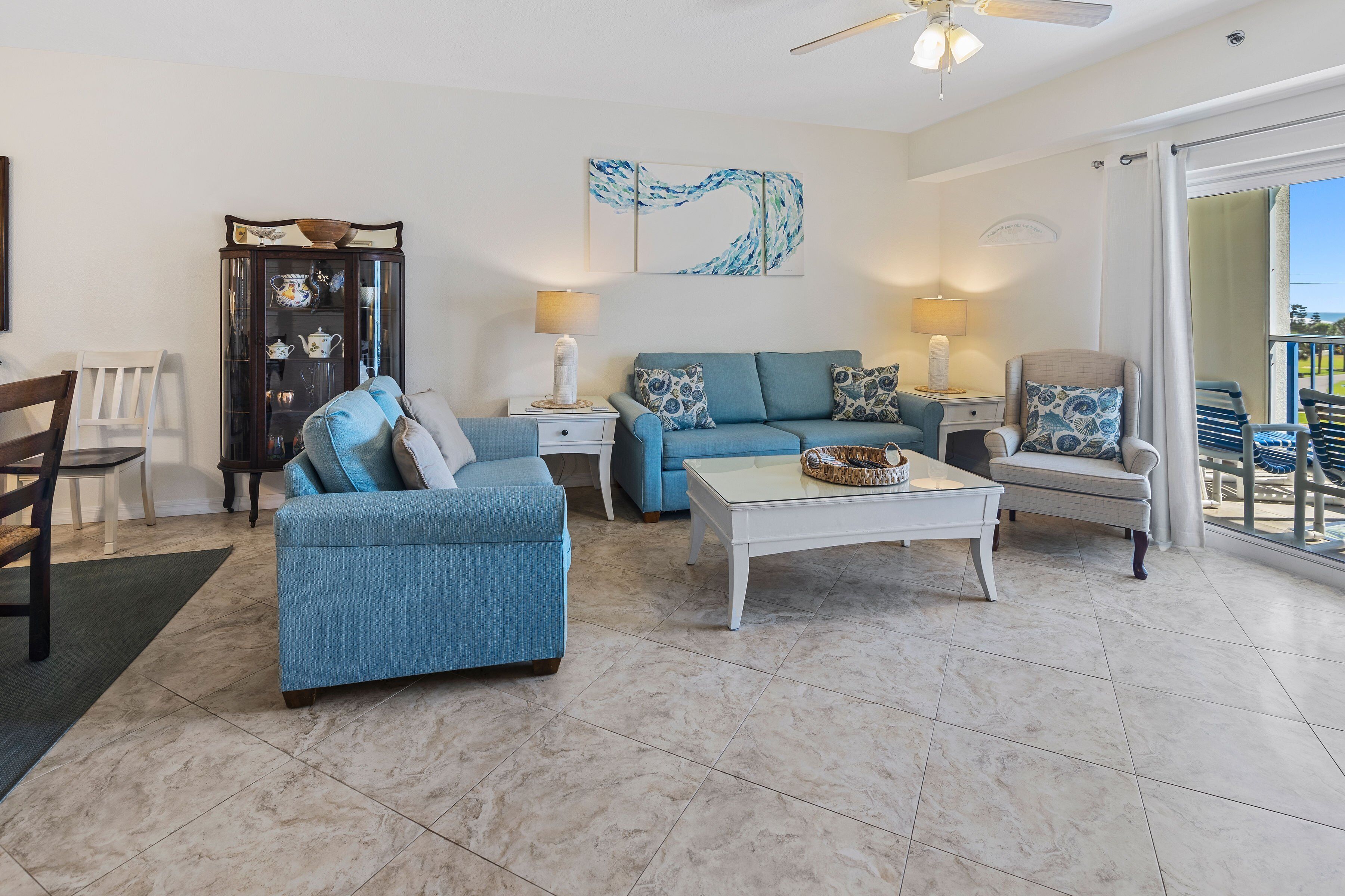 A living room with a blue sofa, a white coffee table, and a glass cabinet.
