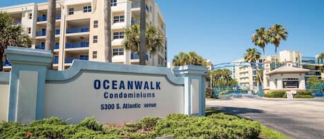 A sign for Oceanwalk Condominiums at 5300 S. Atlantic venue, with a view of the building and palm trees.