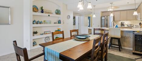 A dining area with a wooden table, chairs, and a kitchen in the background.