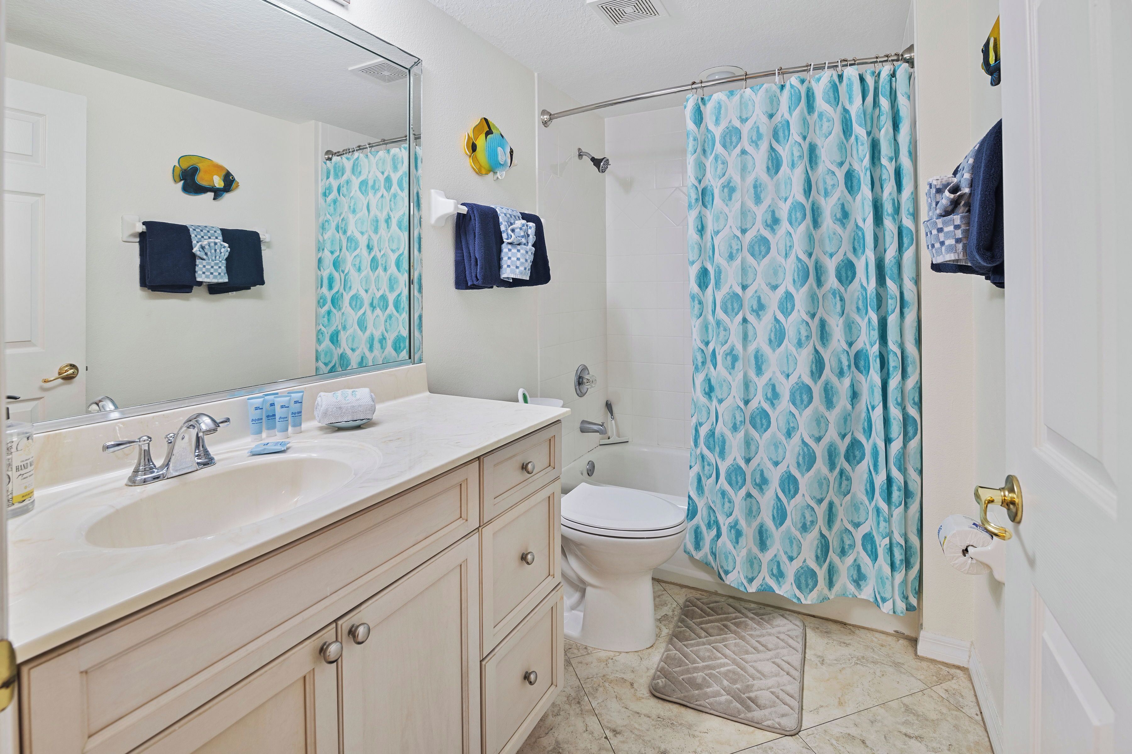 Une salle de bain avec un lavabo blanc, des toilettes, un rideau de douche et un porte-serviettes avec des serviettes.