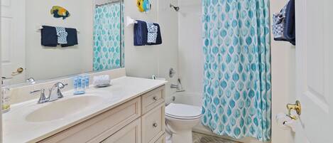 Une salle de bain avec un lavabo blanc, des toilettes, un rideau de douche et un porte-serviettes avec des serviettes.