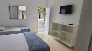 A room with two beds, a TV, and a small open space leading outside. - Pousada Village Maitinga (Bertioga)