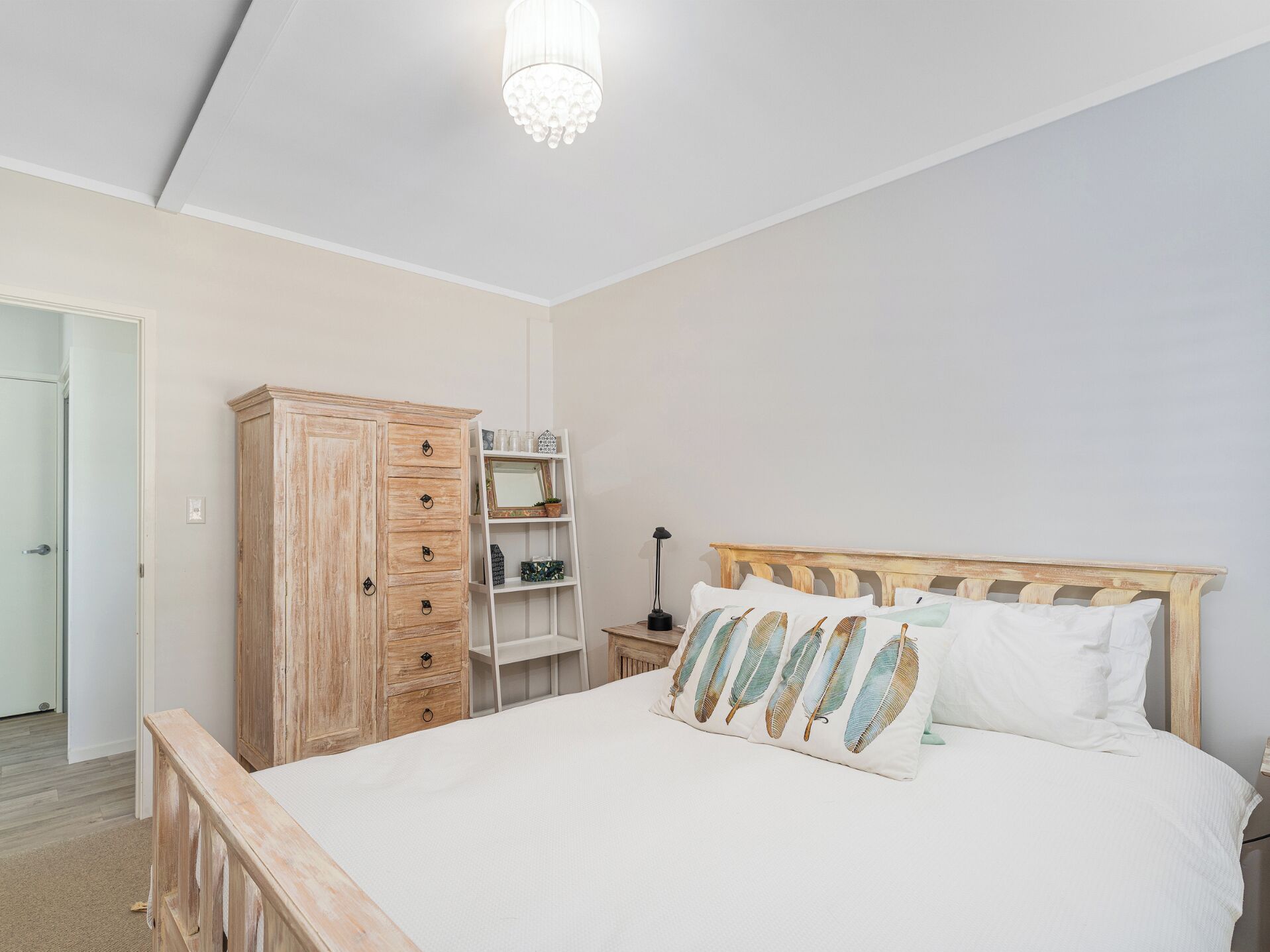 Ein Schlafzimmer mit einem hölzernen Bett, einem Holzschrank, einem weißen Nachttisch und einer Deckenleuchte.