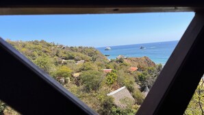 A coastal landscape with a clear view of the sea, rocky outcrops, and scattered buildings.