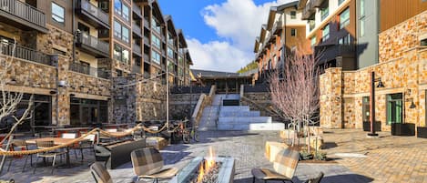 A courtyard with outdoor seating, a fire pit, and a staircase leading to upper floors.