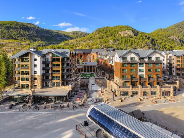 A multi-story hotel with a central courtyard, surrounded by mountains and forest.