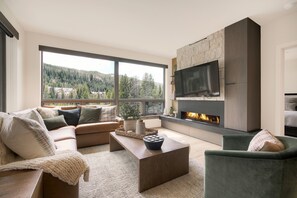 A modern living room with a large window, a fireplace, and a flat-screen TV. - Keystone Luxury 3BR | Balcony, Fireplace & Ski-in (Keystone)
