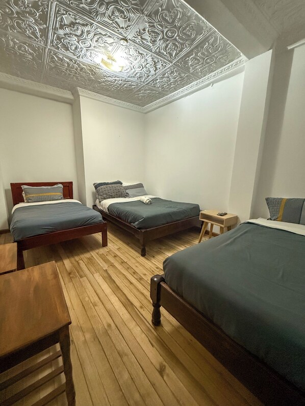 Une chambre avec deux lits, un plancher en bois et un plafond orné de motifs complexes.