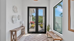 A modern hallway with a wooden bench, a console table, and decorative shells on the wall. - NEW! Luxury 6BR Villa w/ Pool & Spa (Naples)