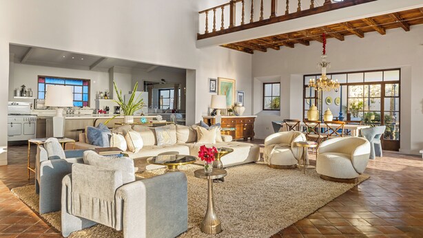 A spacious living area with a high ceiling, a kitchen in the background, and a dining area with a chandelier. - Grand Villa del Mar (Todos Santos)