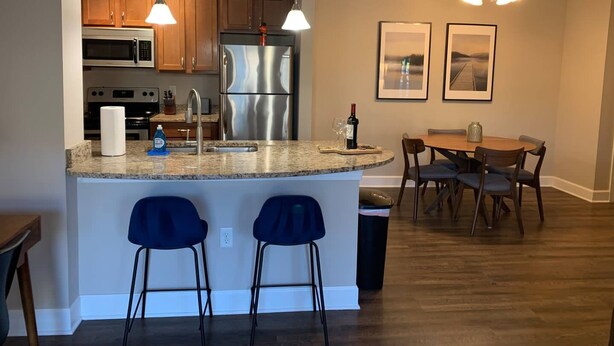 A modern kitchen with granite countertops, stainless steel appliances, and pendant lighting.