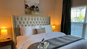 A neatly made bed with a tufted headboard, white bedding, and a tray with toiletries.