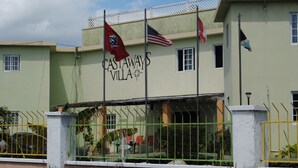 Een gebouw met het bord "CASTAWAYS VILLA" en verschillende vlaggen, waaronder een Amerikaanse vlag.