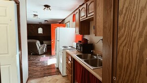 A compact kitchen with wooden cabinets, a refrigerator, a stove, and a microwave.