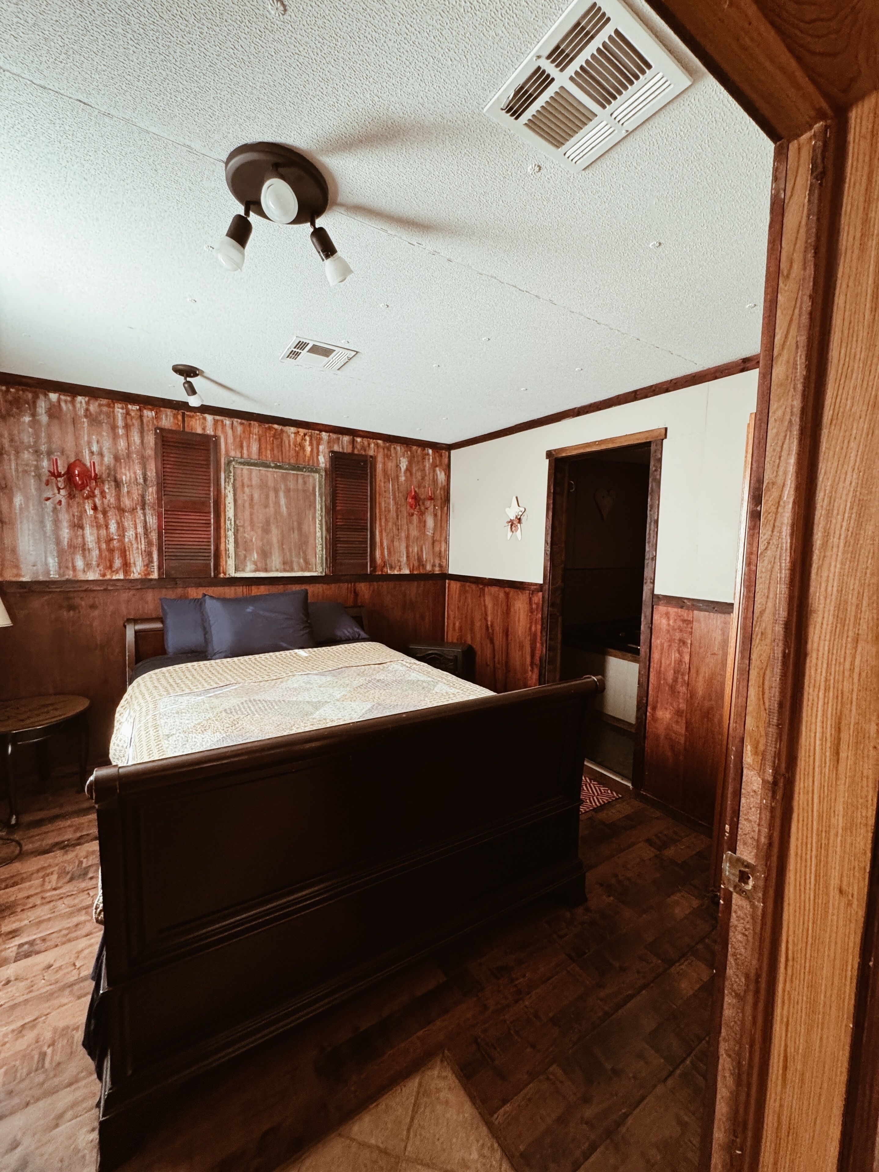 Un dormitorio con una cama de madera, un ventilador de techo y suelo de madera.