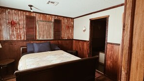 A bedroom with a wooden bed, a ceiling fan, and a wooden floor.