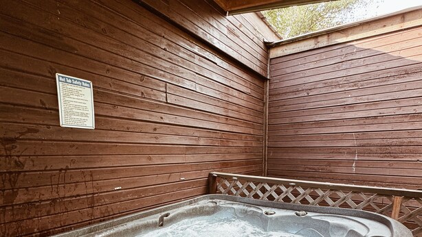 A hot tub in a wooden cabin with a safety notice on the wall.