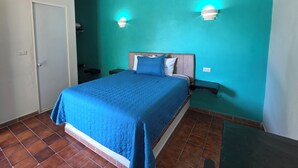 A bedroom with a bed, teal walls, and two wall-mounted lights. - Hotel Tamuín (Tamuín)