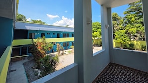 A balcony with a view of a blue and yellow train, greenery, and a clear sky. - Hotel Tamuín (Tamuín)