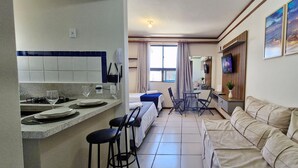 A compact hotel room with a kitchenette, a dining area, and a sofa.