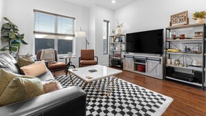 A modern living room with a leather sofa, a coffee table, a TV, and a bookshelf.