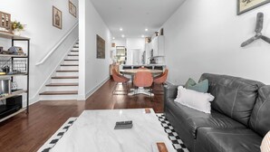 A modern living room with a leather sofa, a coffee table, and a dining area with a table and chairs.