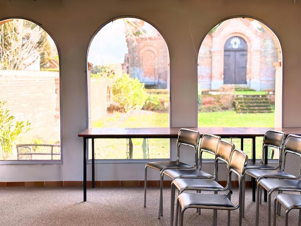 Una habitación con ventanas de arco, una mesa y sillas.