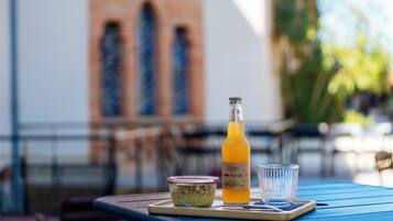 A table with a bottle of orange juice, a glass, and a container of food on a blue table.