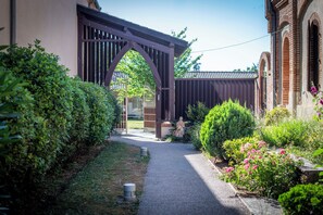Un chemin menant à un bâtiment doté d’une porte en bois de style traditionnel et d’une façade en briques.