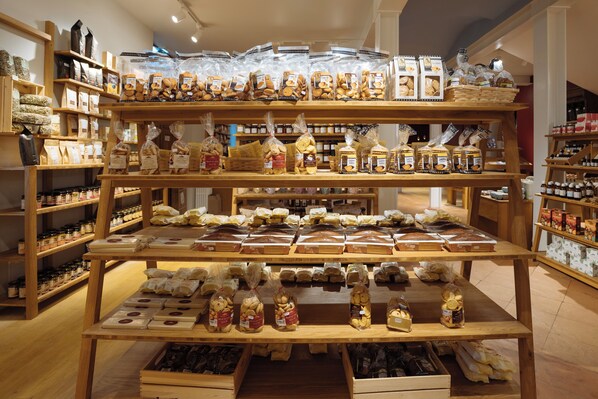 Una panadería con múltiples estantes repletos de panes, pasteles y productos envasados.