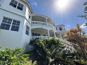 A multi-story building with balconies, large windows, and lush greenery.