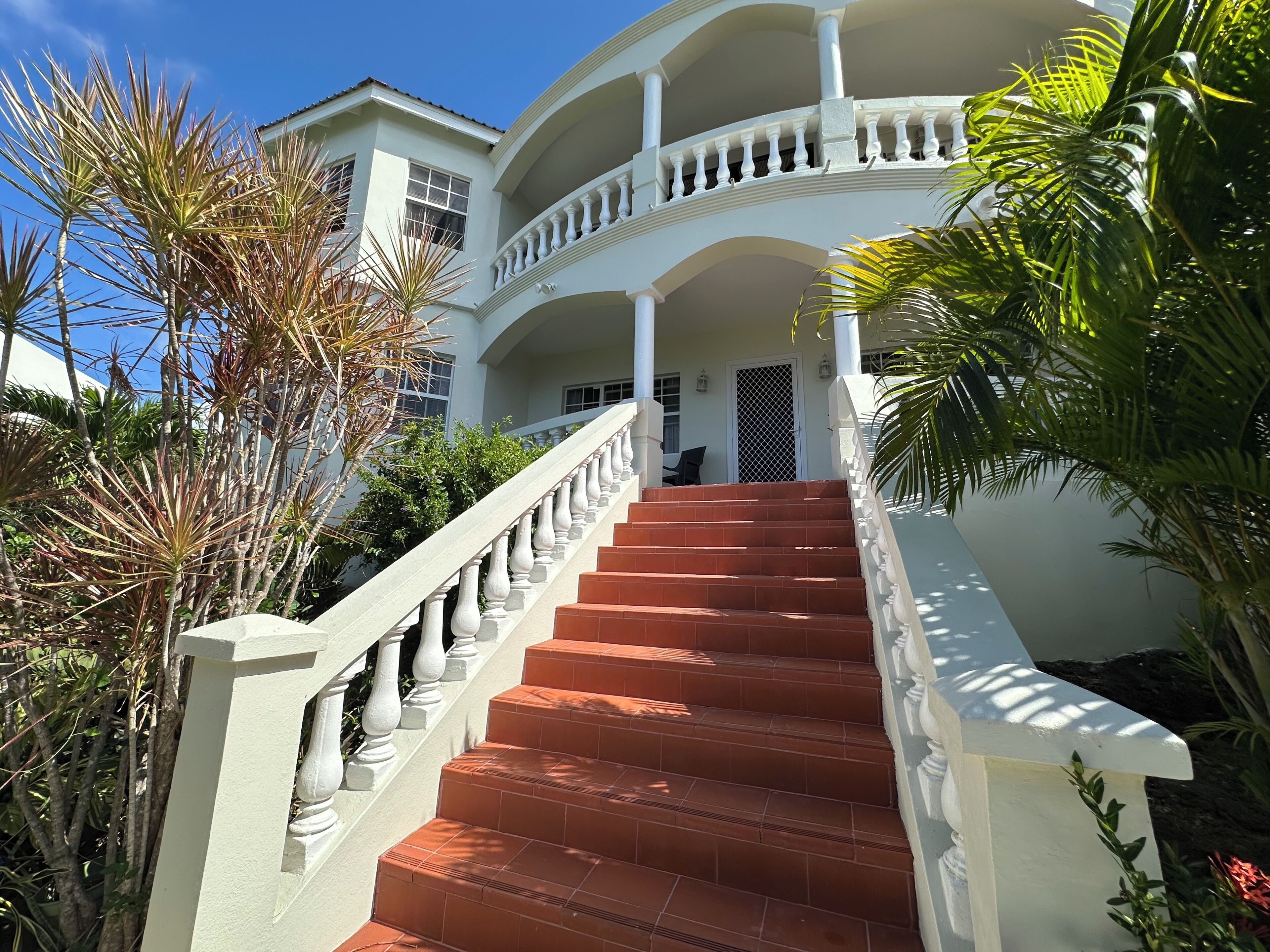 A grand staircase leading to a multi-level building with a white exterior and a balcony.