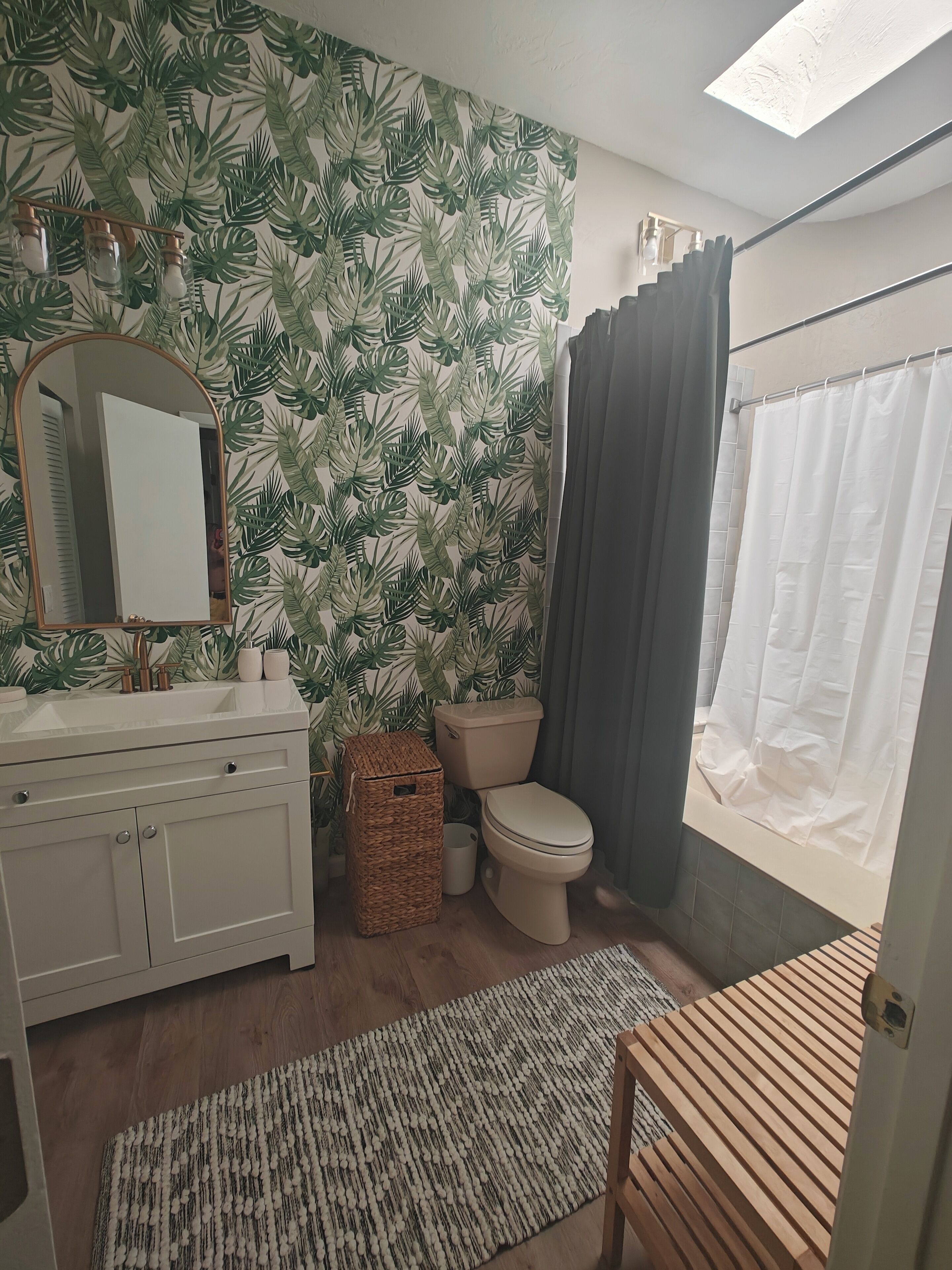 Une salle de bain équipée de toilettes, d’un lavabo, d’un miroir et d’un rideau de douche.