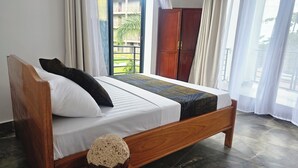 Een netjes opgemaakt bed met een houten frame, witte beddengoed en een decoratieve plaid.