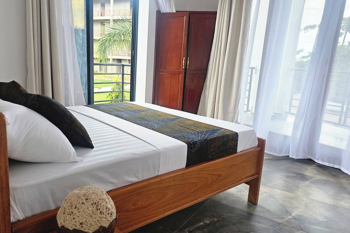 A neatly made bed with a wooden frame, white bedding, and a decorative throw.
