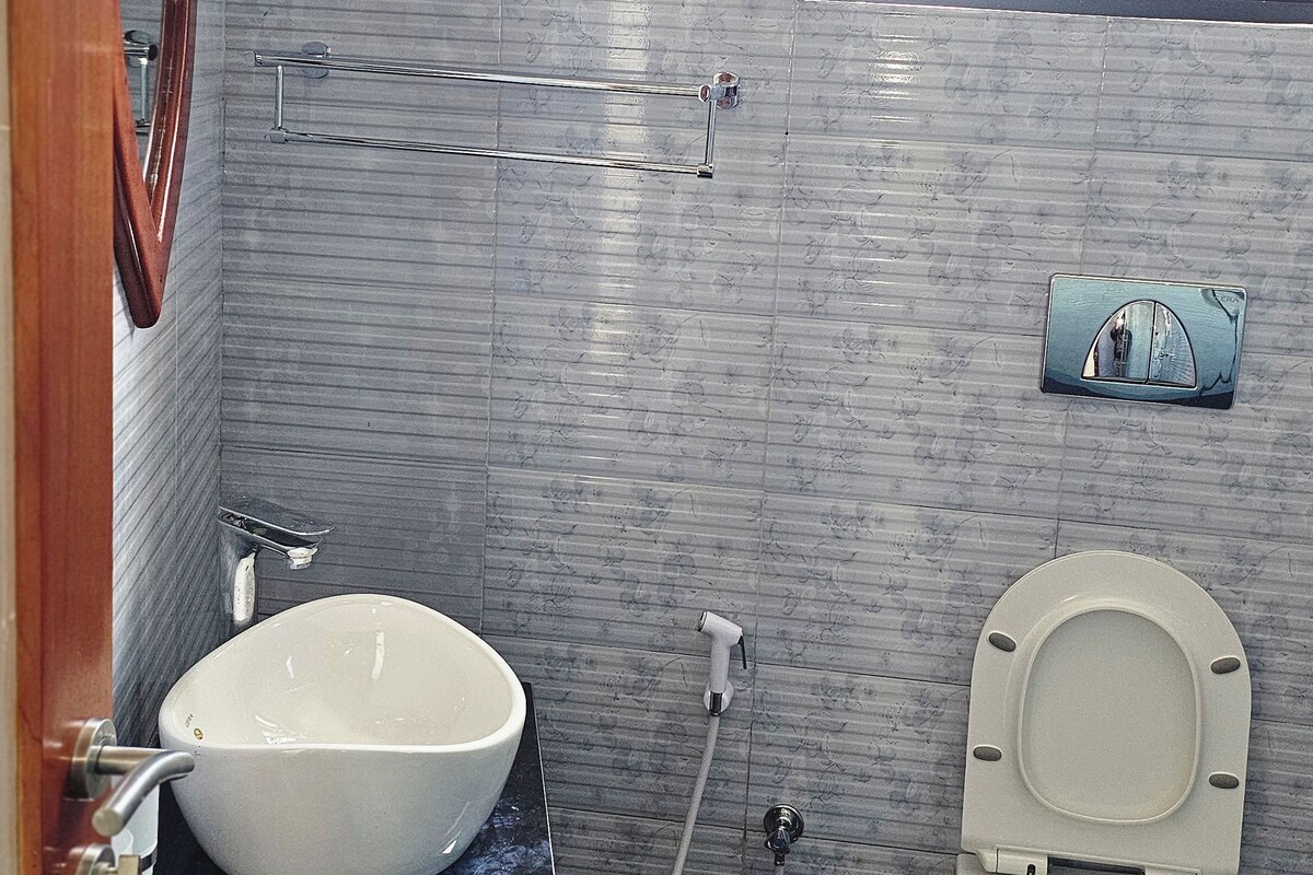 Un baño con un lavamanos blanco, un inodoro, un perchero para toallas y una ventana.