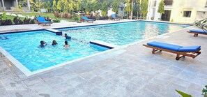 Una piscina al aire libre, sillones reclinables de piscina