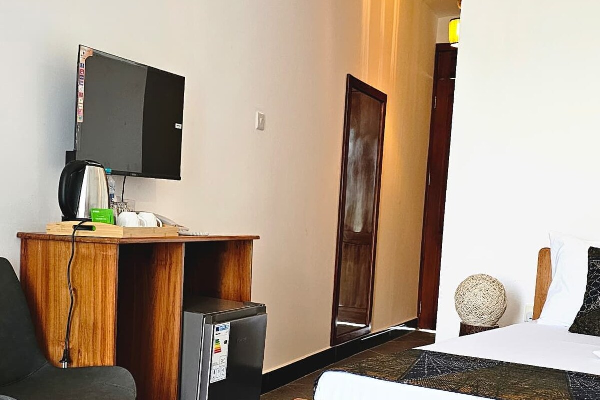 Une chambre d’hôtel équipée d’un lit, d’un bureau, d’une chaise, d’une télévision et d’une petite armoire.