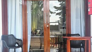 Een hotelingang met een houten deur, twee stoelen, een tafel en een plafondlamp.