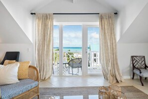 Una habitación con balcón, mobiliario de mimbre y vista al océano.