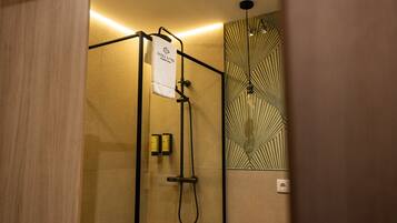 Un espacio de ducha con toallero, puerta de vidrio y pared con diseño.