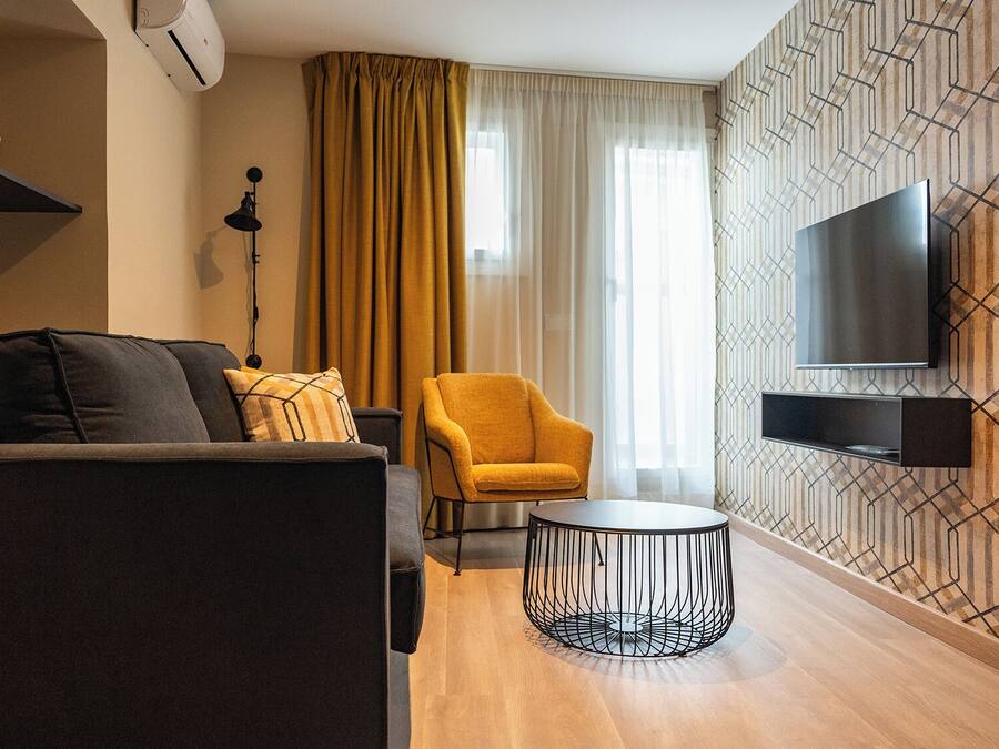 A modern living room with a sofa, armchair, and round coffee table.