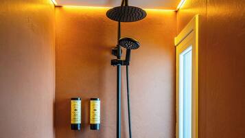 A shower with a handheld showerhead and a wall-mounted control panel.