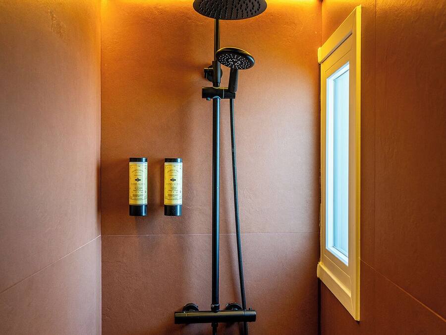 A shower with a handheld showerhead and a wall-mounted control panel.