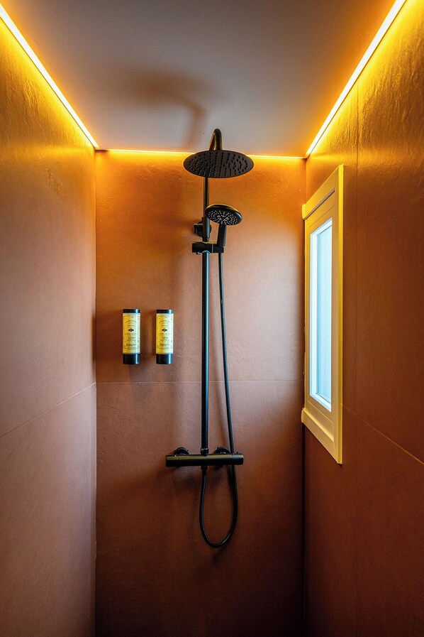 A shower with a handheld showerhead and a wall-mounted control panel.
