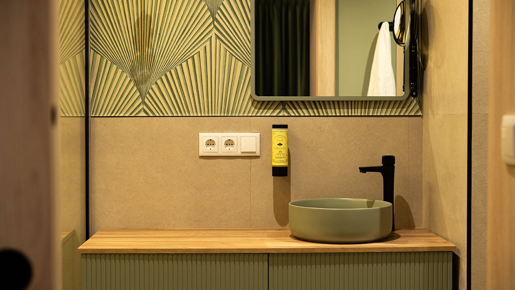 Un baño moderno con un lavabo redondo, un espejo y un perchero para toallas.