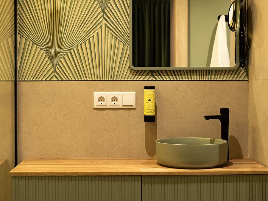 Un baño moderno con un lavabo redondo, un espejo y un perchero para toallas.