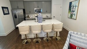 A modern kitchen with a central island, stainless steel appliances, and a dining area with bar stools.