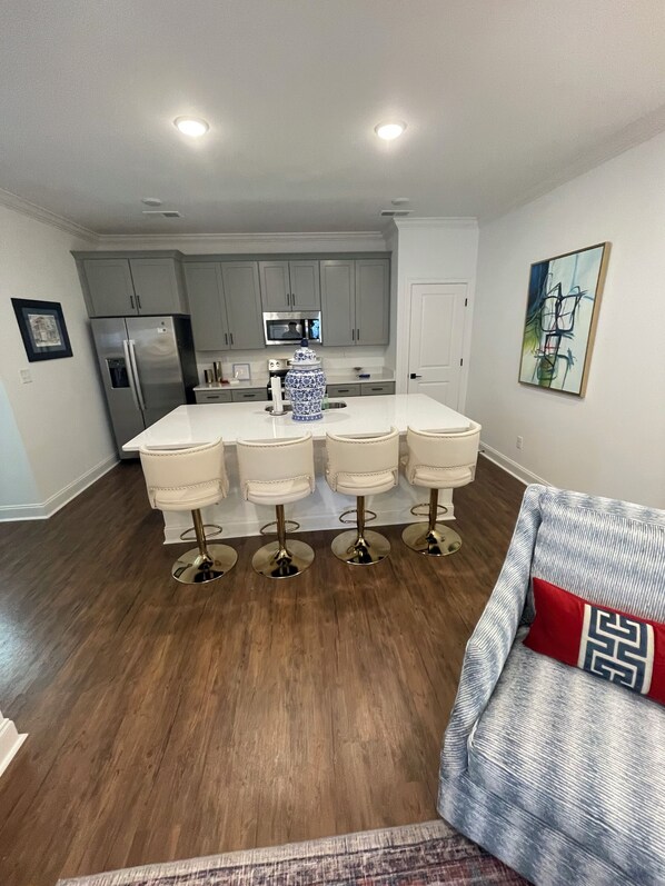 A modern kitchen with a central island, stainless steel appliances, and a dining area with bar stools.